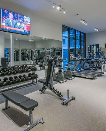 a gym with weights and cardio equipment and a television